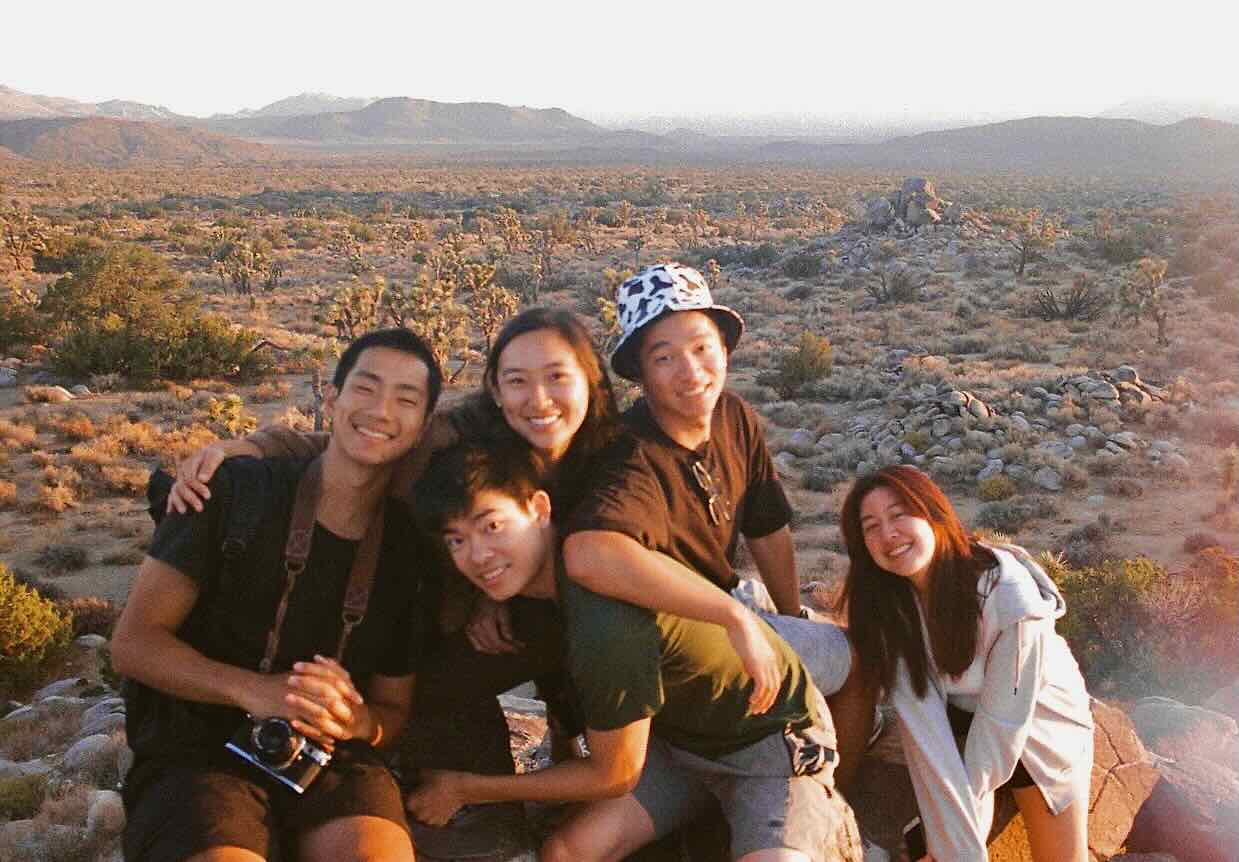 Friends sitting together on rocks above the desert landscape in joshua tree national park.