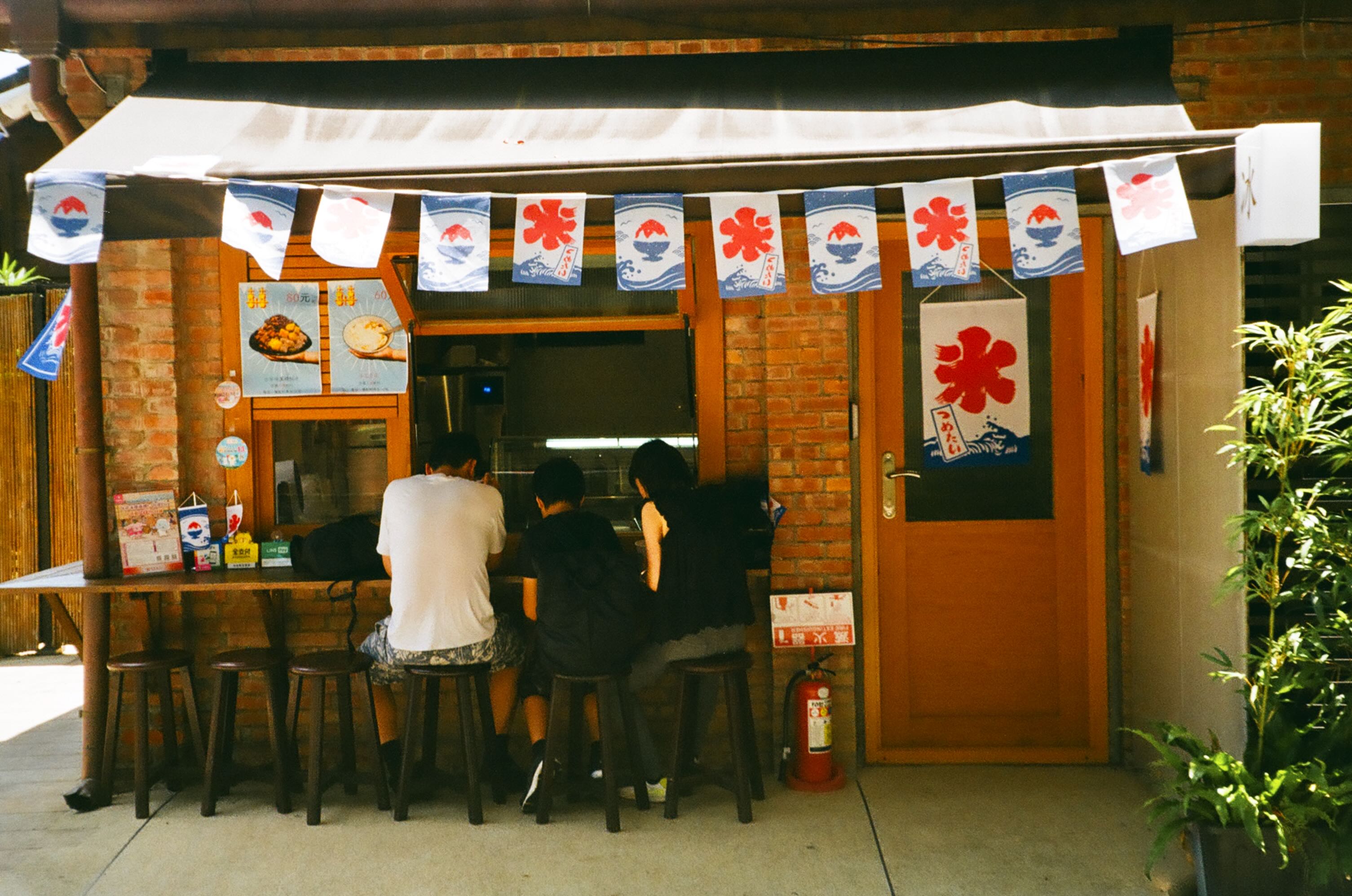 Customers seated at a small shop decorated with shaved-ice banners at rongjin gorgeous time in taipei.